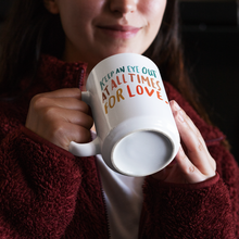Load image into Gallery viewer, Brunette female in cozy red fleece sweater holding a white coffee mug with a beautiful, colourful quote about love on it.
