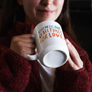 Brunette female in cozy red fleece sweater holding a white coffee mug with a beautiful, colourful quote about love on it.