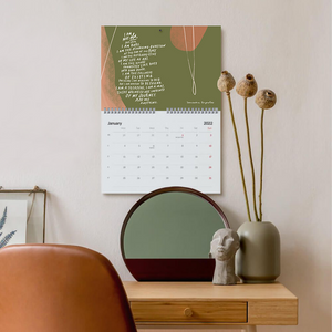 Mockup of horizontal letter-size spiral bound calendar for 2022 with punch hole for hanging on wall for home or office, featuring 'I am not old' poem for January. Poems and colourful abstract art for each month of the year by bentlily, Samantha Reynolds. Printed on demand by Gelato.