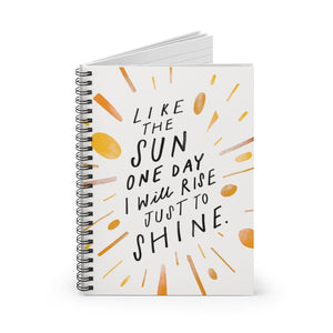 Spiral notebook, standing up on table, showing the cover with a big, creative, cool quote about living your best life. 