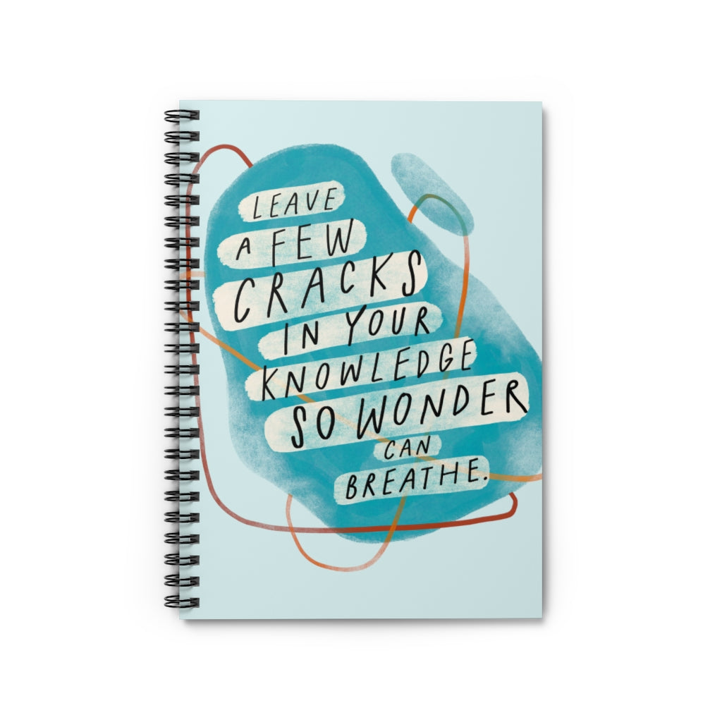 Spiral blue 6” x 8” notebook with abstract shapes and a hand-lettered inspirational quote on the cover about wonder. 