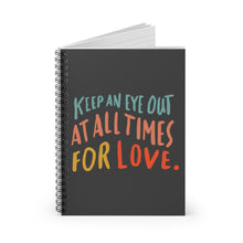 Load image into Gallery viewer, Black spiral notebook, standing up on table, showing the cover with an inspiring quote about love in colorful font. 
