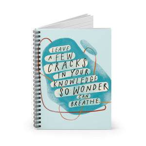 Spiral notebook, standing up on table, showing the whimsical, illustrated cover featuring an inspiring quote about wonder.