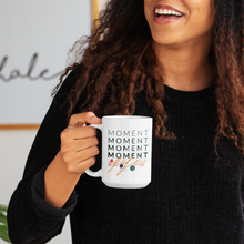 Load image into Gallery viewer, Woman smiling in black sweater with brown curly hair, holding a cool white 15oz coffee mug with mindfulness quote printed on it.
