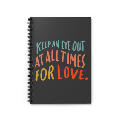 Inspiring quote about love printed in colorful big lettering on a black spiral A5 notebook. 