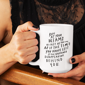 Woman’s hands with black nail polish holding funky white 15 oz coffee mug with motivational quote on it in black lettering.  