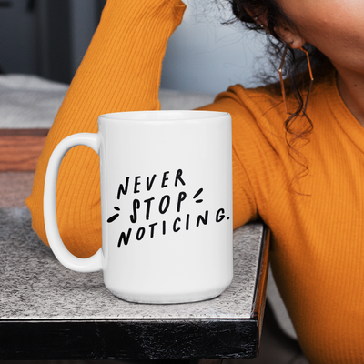 Minimalist 15 oz white coffee mug decorated with stark black hand-lettered quote about mindfulness.
