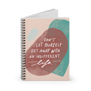 Earth-toned spiral notebook, standing up on table, showing the cover with an inspiring quote and whimsical shapes. 