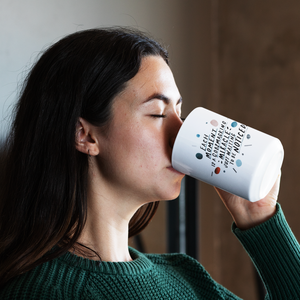 Profile of brunette woman in green sweater drinking from a creative, large coffee mug with quote on it about mindfulness.