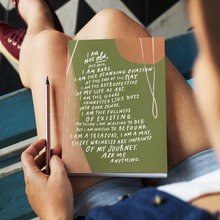 Load image into Gallery viewer, Woman with hardcover journal on her lap featuring the poem, “I Am Not Old” by Samantha Reynolds on the cover.
