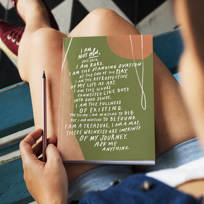 Front view of hardcover journal with beautiful abstract green and pink art featuring the poem, “I Am Not Old” by Samantha Reynolds on the cover.