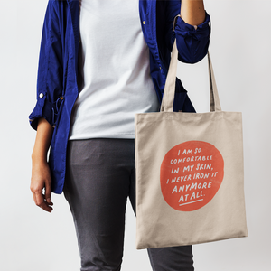 Woman in casual outfit holding natural cotton tote bag printed on front with positive, clever, cute message about aging